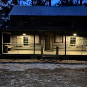 A wooden cabin with porch lights at night.