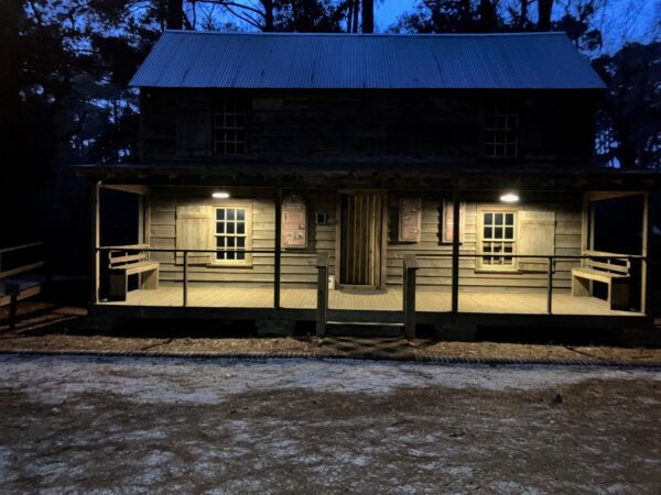 A wooden cabin with porch lights at night.